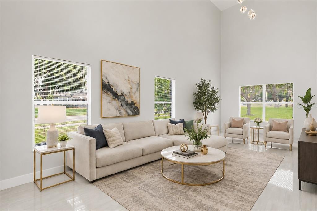 A bright living room features a beige sectional sofa, a marble coffee table, and high ceilings — 1005 CHASE DRIVE, WINTER GARDEN, FL