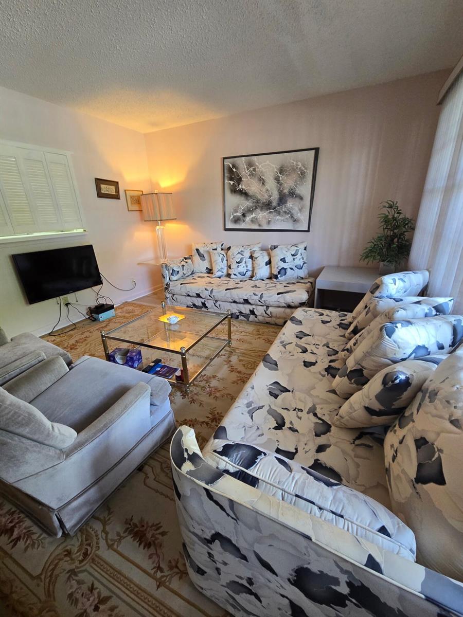 A living room features two patterned sofas, a glass coffee table, and a gray armchair — 1010 Berkshire A, Deerfield Beach FL 33442, DEERFIELD BEACH, FL