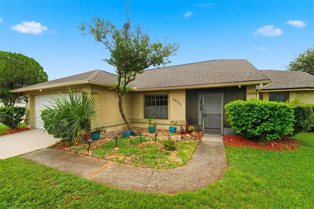 A single-story house with a tan stucco exterior, a screened entryway, and a landscaped yard — 20753 MAXIM PARKWAY, ORLANDO, FL