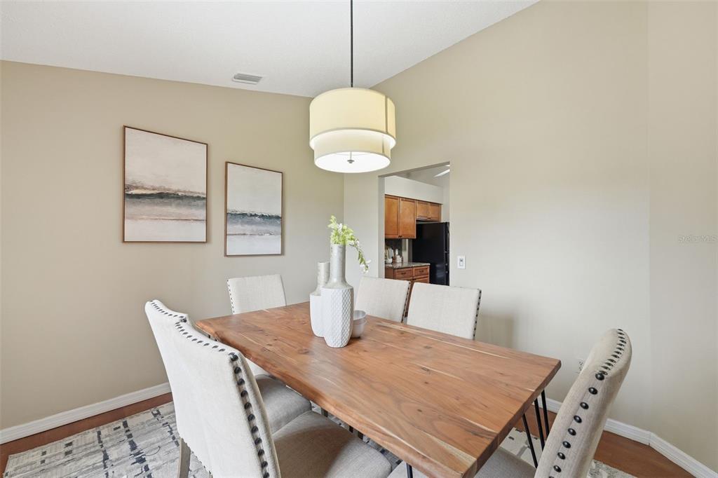 A dining room features a wooden table, upholstered chairs, a pendant light, and wall art — 20753 MAXIM PARKWAY, ORLANDO, FL