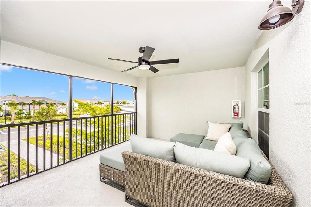 A covered balcony features a wicker sectional sofa, a ceiling fan, and a metal railing — 17470 OPAL SAND DRIVE UNIT 205, VENICE, FL