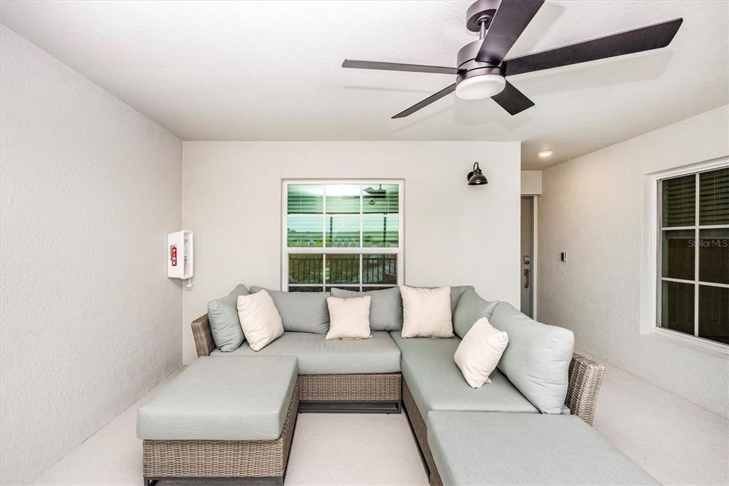 A covered patio features a large sectional sofa, a ceiling fan, and two windows — 17470 OPAL SAND DRIVE UNIT 205, VENICE, FL