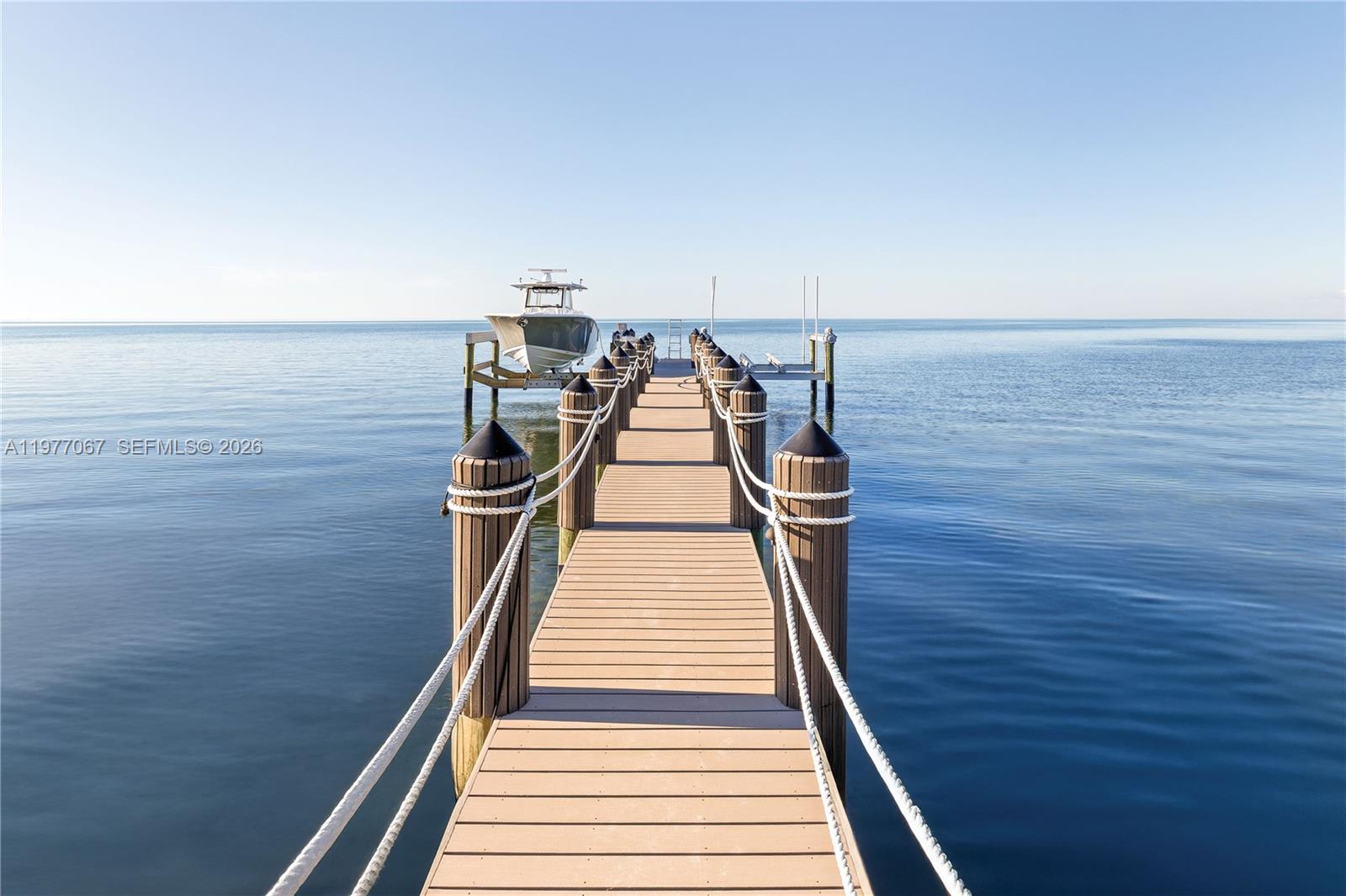 A wooden pier extends into calm water with a boat docked on a lift — 57783 Morton Street, Marathon FL 33050, MARATHON, FL