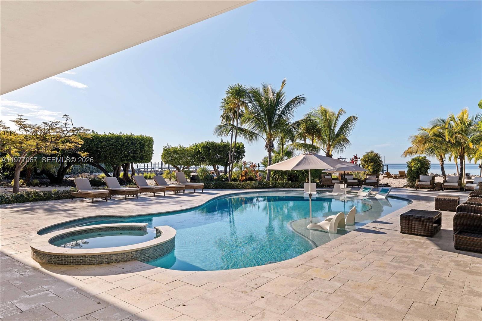 A swimming pool with an integrated hot tub sits on a stone patio by the ocean — 57783 Morton Street, Marathon FL 33050, MARATHON, FL