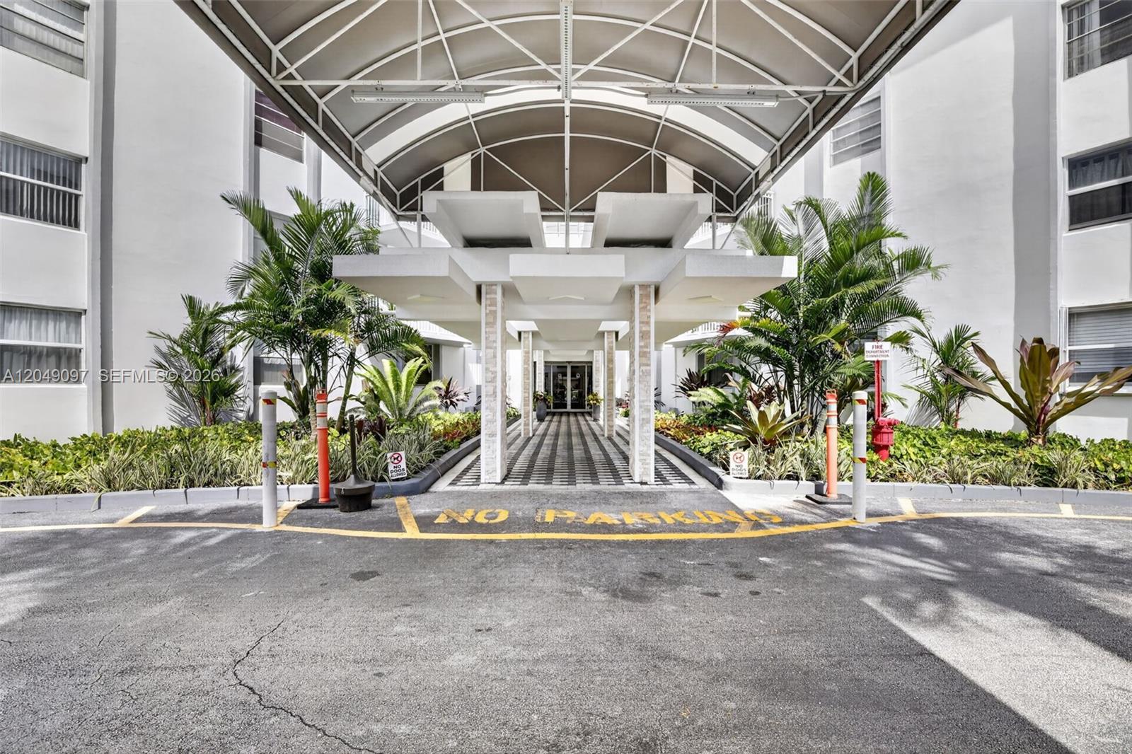 A covered entrance with a checkered walkway leads to a building with palm trees — 1913 S Ocean Dr # 225, Hallandale Beach FL 33009, HALLANDALE BEACH, FL