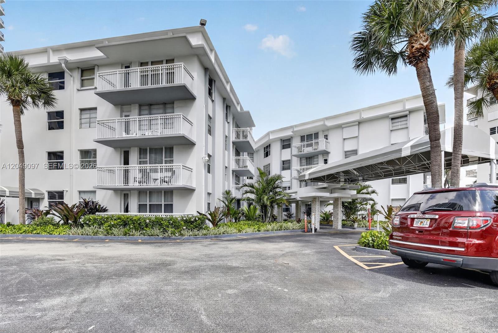 A multi-story white apartment building features balconies and a covered entrance with a red SUV — 1913 S Ocean Dr # 225, Hallandale Beach FL 33009, HALLANDALE BEACH, FL