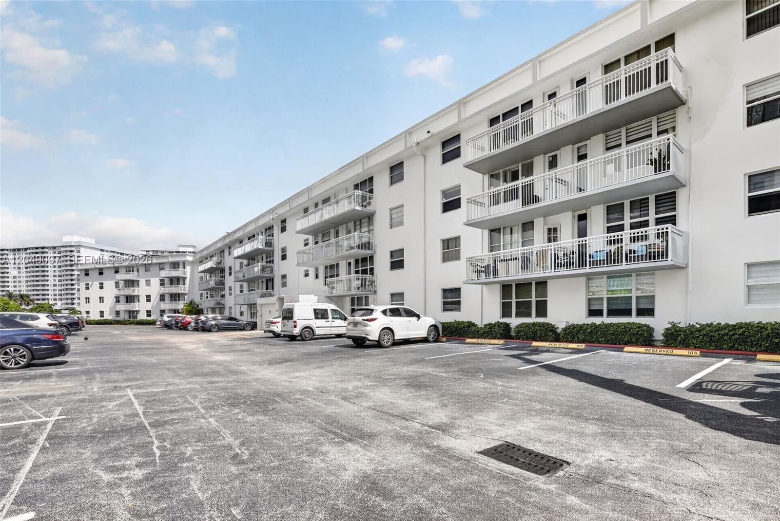 A multi-story white apartment building with balconies overlooks a paved parking lot — 1913 S Ocean Dr # 225, Hallandale Beach FL 33009, HALLANDALE BEACH, FL