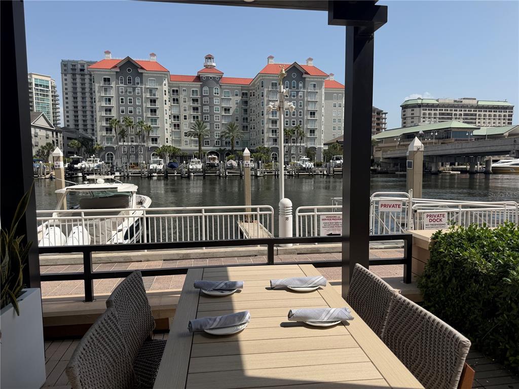 An outdoor dining area overlooks a marina with boats and a large waterfront building — 700 S HARBOUR ISLAND BOULEVARD UNIT 512, TAMPA, FL
