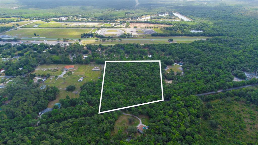 An aerial view shows a wooded lot outlined in white surrounded by rural residential properties — 651 S COUNTY ROAD 13, ORLANDO, FL