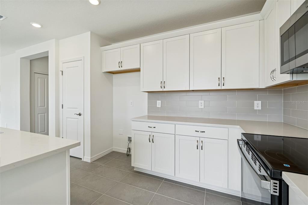 A kitchen features white cabinets, gray subway tile backsplash, and light-colored countertops — 4311 OUTHAUL RUN, PALMETTO, FL