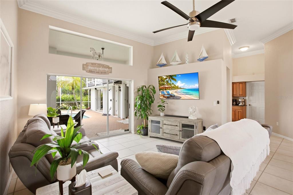 A living room features tile floors, a ceiling fan, a wall-mounted television, and sliding glass doors — 1241 NEAPOLITAN ROAD, PUNTA GORDA, FL