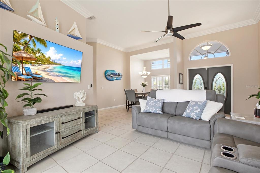 A living room features a large television, gray sofa, tile flooring, and coastal decor — 1241 NEAPOLITAN ROAD, PUNTA GORDA, FL