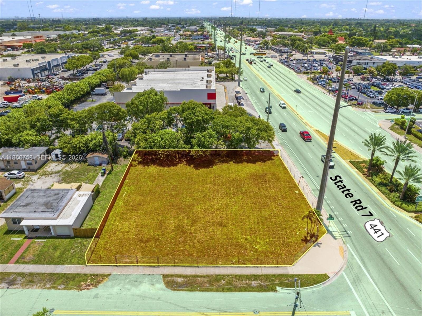 An aerial view shows a vacant, fenced rectangular lot adjacent to a busy highway — 1501 S State Road 7 Rd, Hollywood FL 33023, HOLLYWOOD, FL