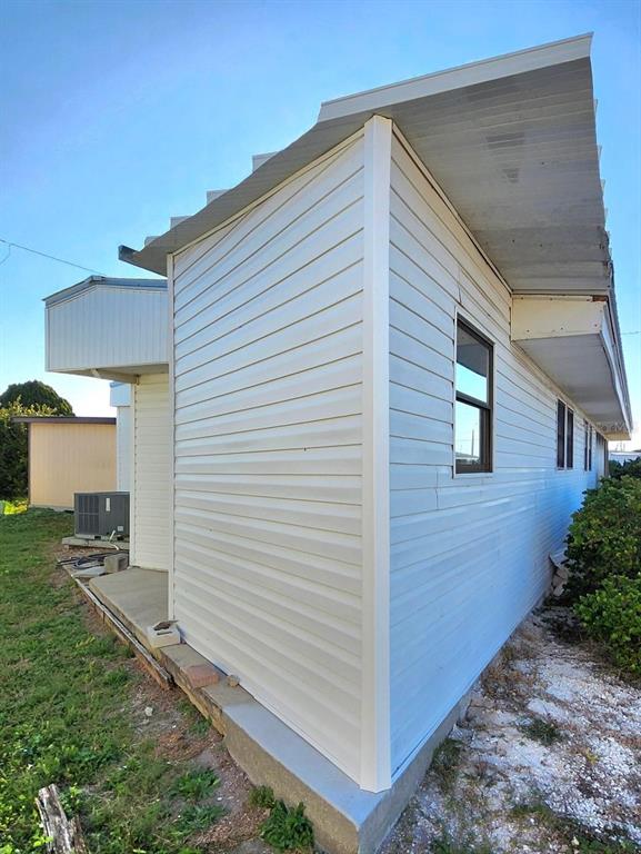 The exterior of a light-colored vinyl-sided home features a metal roof and a concrete foundation — 2003 MINNESOTA AVENUE, BRADENTON, FL