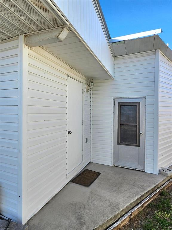 A concrete patio area features two white doors and white horizontal vinyl siding — 2003 MINNESOTA AVENUE, BRADENTON, FL