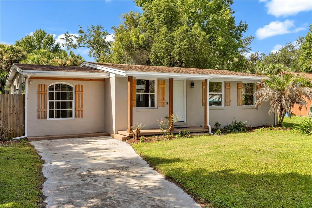 A single-story house with a beige stucco exterior, a concrete driveway, and a small porch — 247 TOMS ROAD, DEBARY, FL