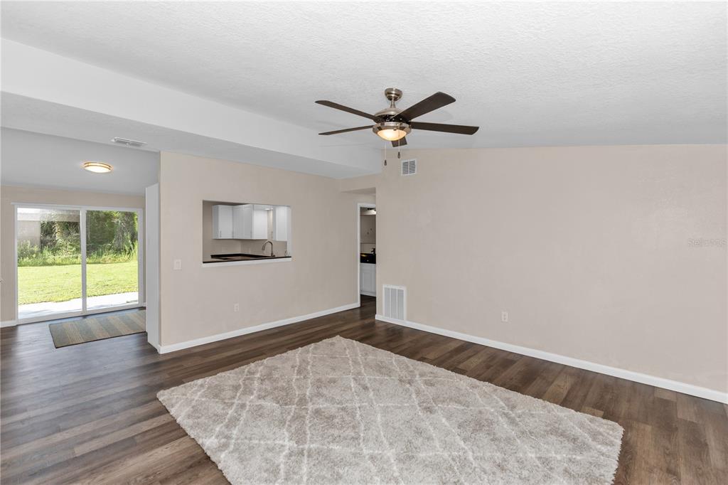 A living room with wood-look flooring, a ceiling fan, and a pass-through to the kitchen — 247 TOMS ROAD, DEBARY, FL