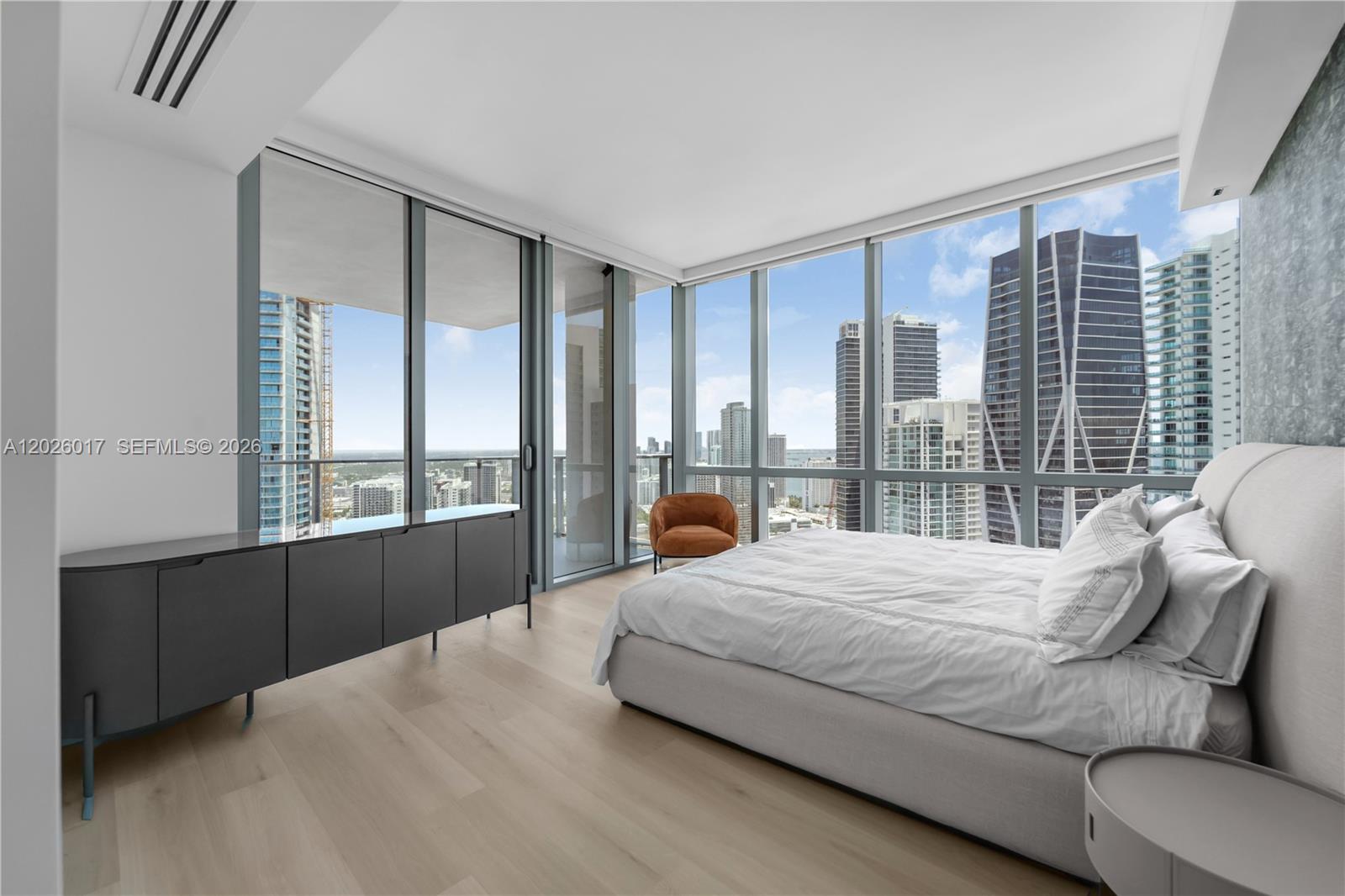 A modern bedroom features floor-to-ceiling windows, light wood flooring, and a view of city skyscrapers — 851 NE 1st Ave # 4201, Miami FL 33132, MIAMI, FL