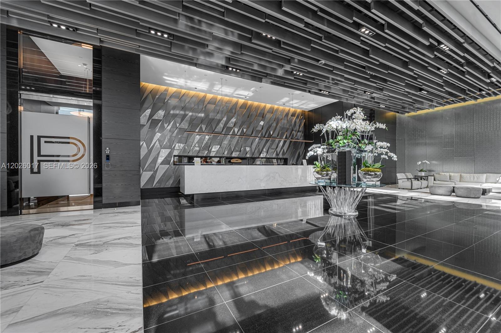 A modern lobby features a marble reception desk, dark tiled floors, and a geometric ceiling — 851 NE 1st Ave # 4201, Miami FL 33132, MIAMI, FL
