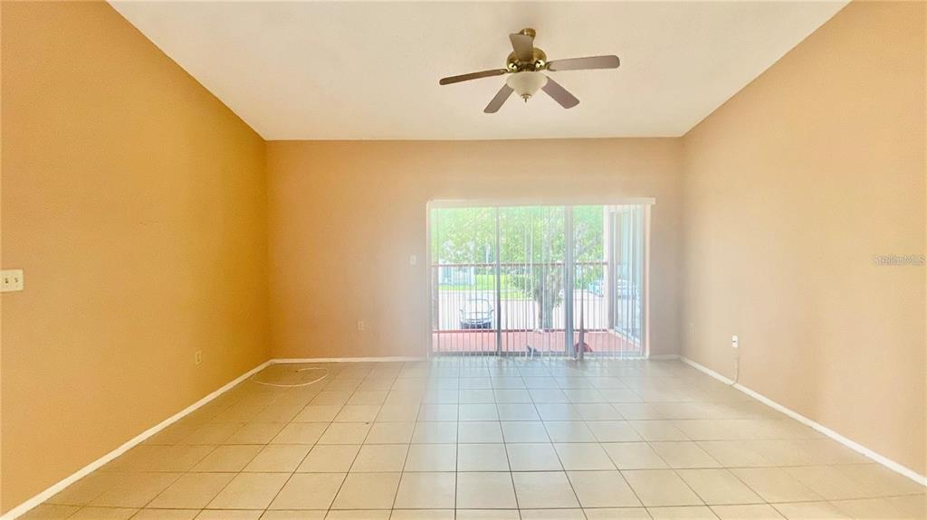 An empty room with beige walls, tile flooring, a ceiling fan, and sliding glass doors — 2528 CITRUS CLUB LANE UNIT 206, ORLANDO, FL