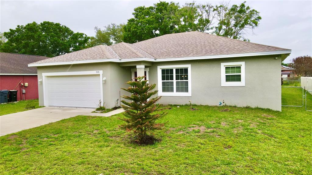 A single-story house with a light green stucco exterior, a garage, and a front lawn — 535 GULL DRIVE, KISSIMMEE, FL