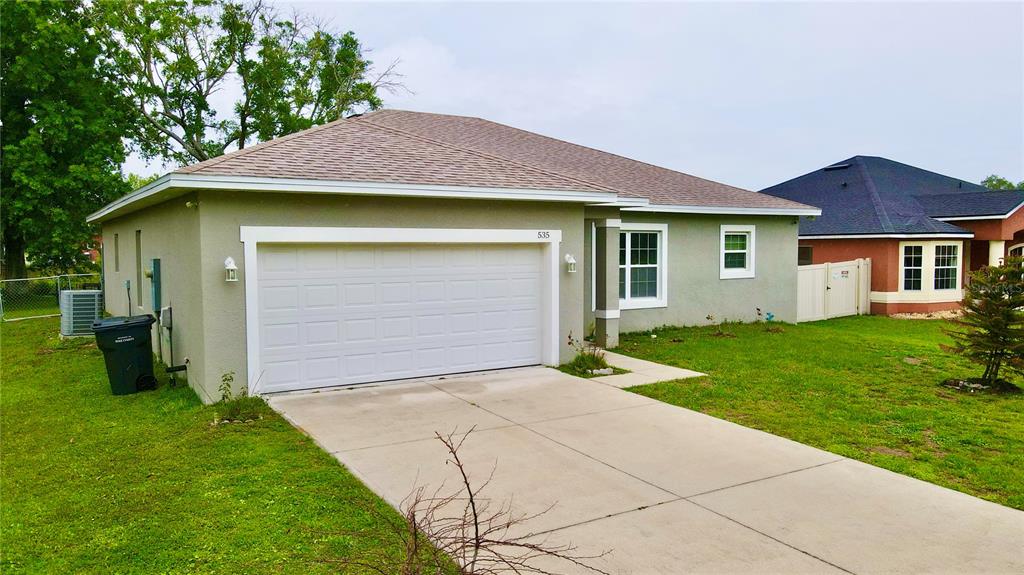 A single-story house with a beige stucco exterior, a two-car garage, and a concrete driveway — 535 GULL DRIVE, KISSIMMEE, FL