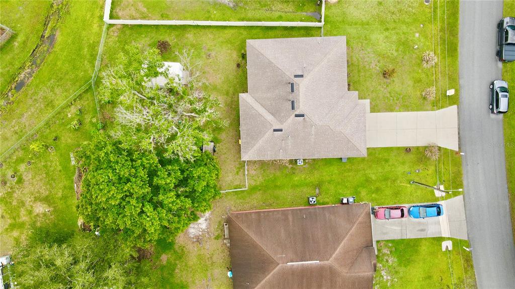 An aerial view shows two houses with driveways, a large tree, and a fenced yard — 535 GULL DRIVE, KISSIMMEE, FL