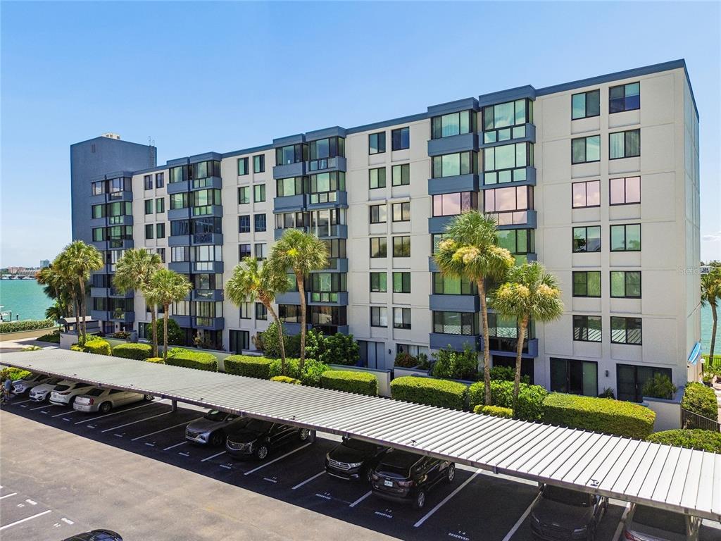 A multi-story apartment building with a covered parking lot and palm trees in front — 644 ISLAND WAY UNIT 405, CLEARWATER, FL