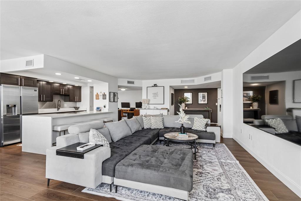 A modern open-concept living room features a large sectional sofa, kitchen island, and dark cabinetry — 644 ISLAND WAY UNIT 405, CLEARWATER, FL