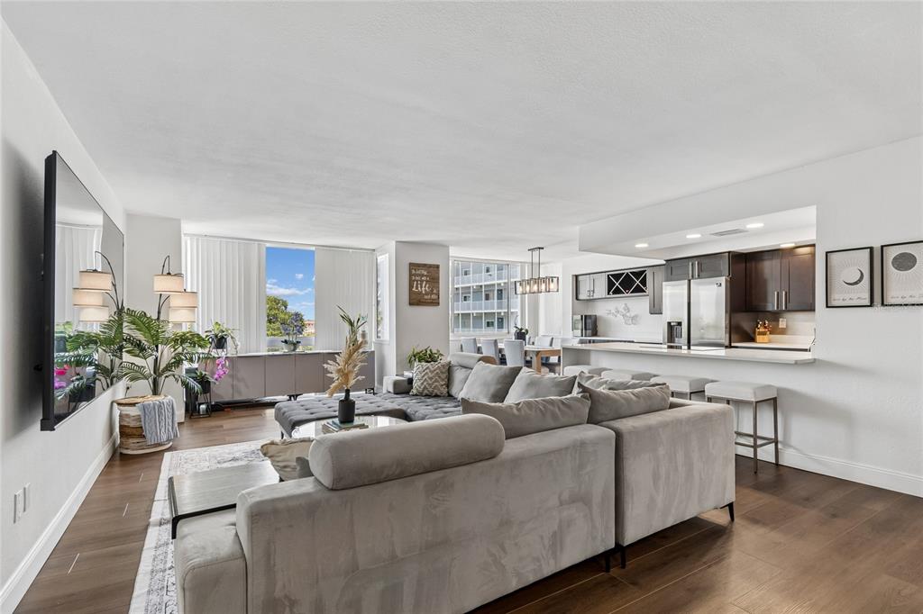 A living room with a large gray sectional sofa, open kitchen, and floor-to-ceiling windows — 644 ISLAND WAY UNIT 405, CLEARWATER, FL