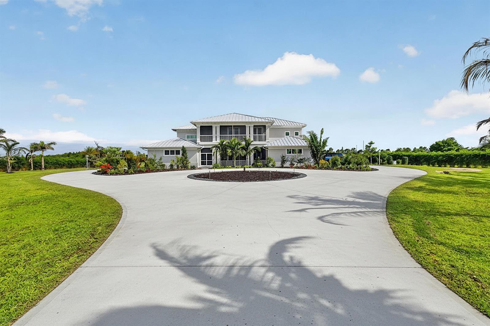 A two-story house with a metal roof sits behind a large circular concrete driveway — 2985 SW Trailside Path, Stuart FL 34997, STUART, FL