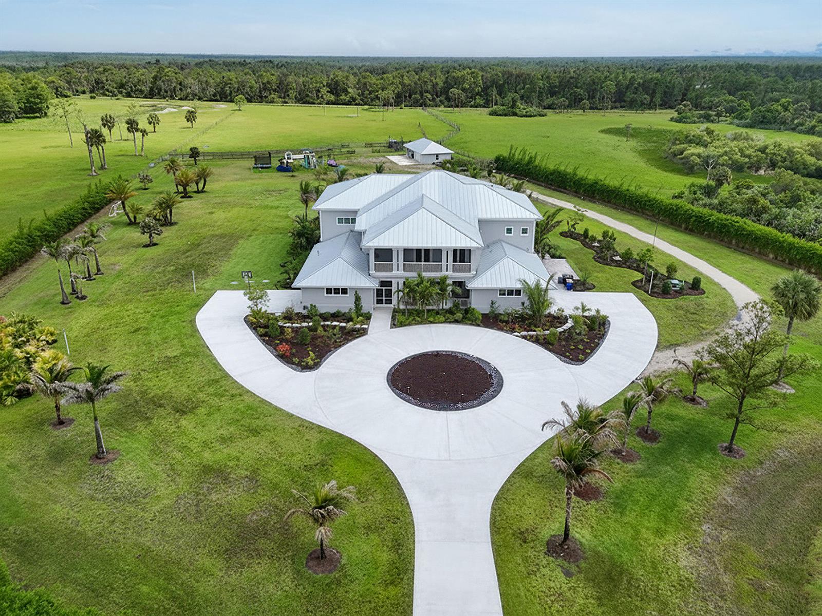 An aerial view of a large two-story house with a metal roof and circular driveway — 2985 SW Trailside Path, Stuart FL 34997, STUART, FL