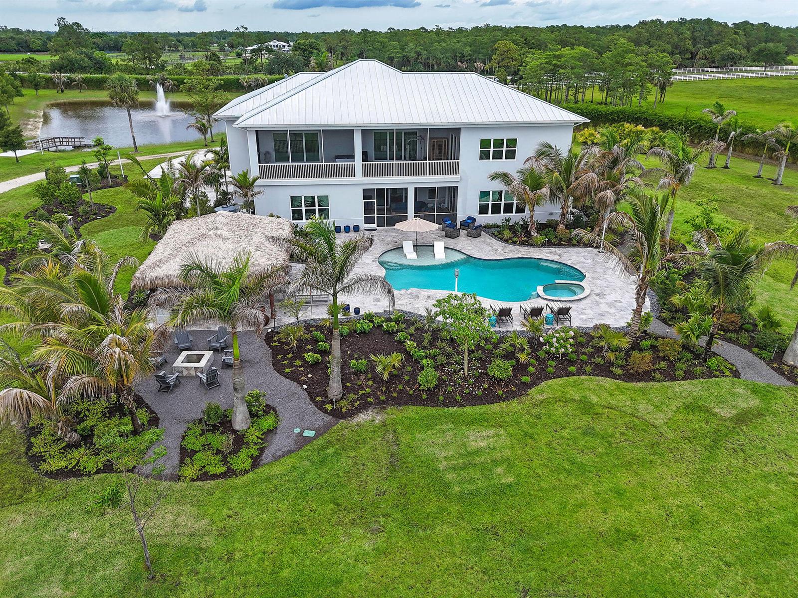 An aerial view shows a two-story house with a pool, tiki hut, and fire pit — 2985 SW Trailside Path, Stuart FL 34997, STUART, FL