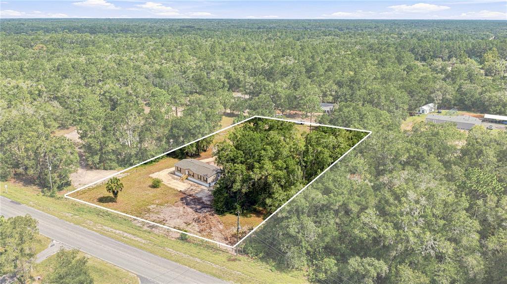 An aerial view shows a single-story house situated on a large, partially wooded lot — 7314 W EDWARDIAN STREET, DUNNELLON, FL