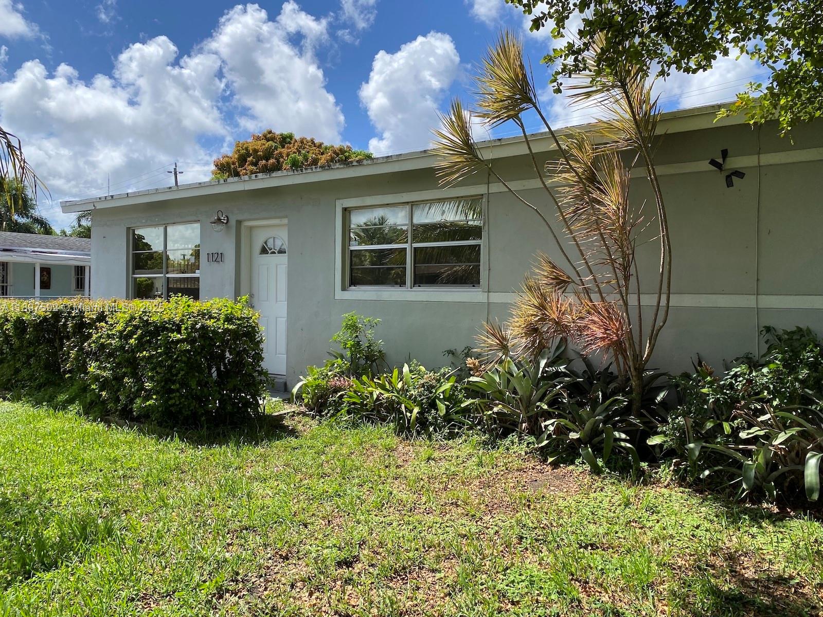 A single-story house with a light gray exterior, white door, and front yard landscaping — 1121 NE 214th St, Miami FL 33179, MIAMI, FL