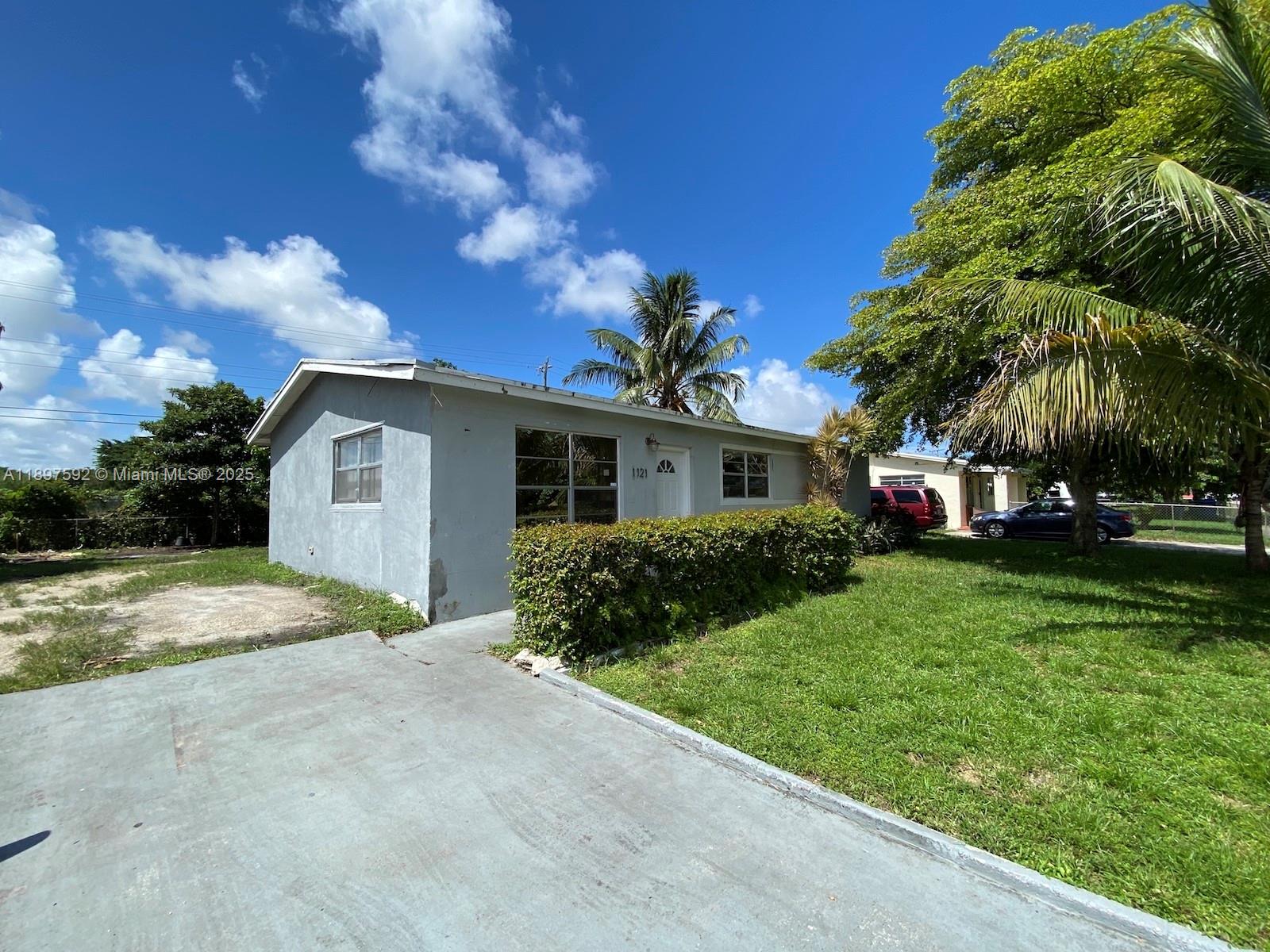 A single-story gray house with a concrete driveway and a manicured hedge in front — 1121 NE 214th St, Miami FL 33179, MIAMI, FL