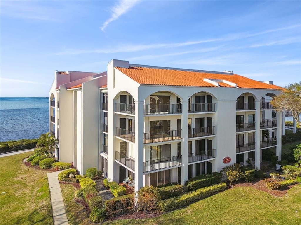 An exterior view of a multi-story apartment building with balconies overlooking the water — 301 MARINER DRIVE UNIT 301, TARPON SPRINGS, FL