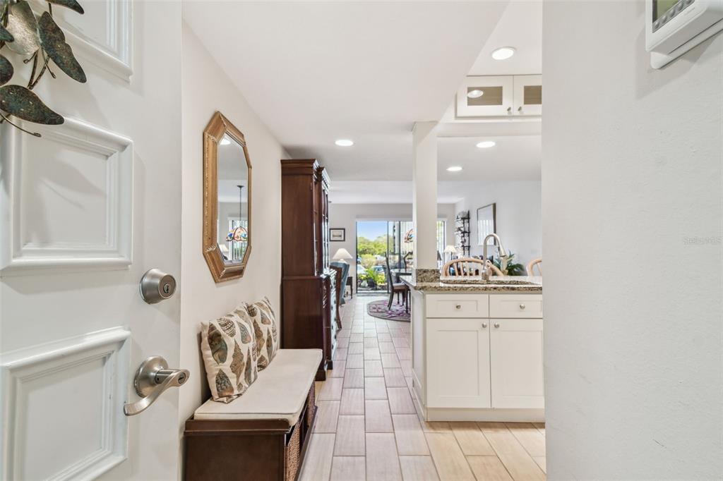 An entryway with a bench and mirror leads into a kitchen and living area — 301 MARINER DRIVE UNIT 301, TARPON SPRINGS, FL