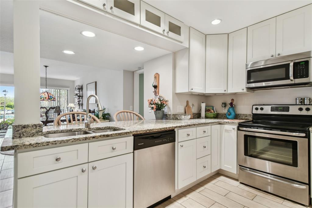 A kitchen features white cabinets, granite countertops, stainless steel appliances, and a breakfast bar — 301 MARINER DRIVE UNIT 301, TARPON SPRINGS, FL