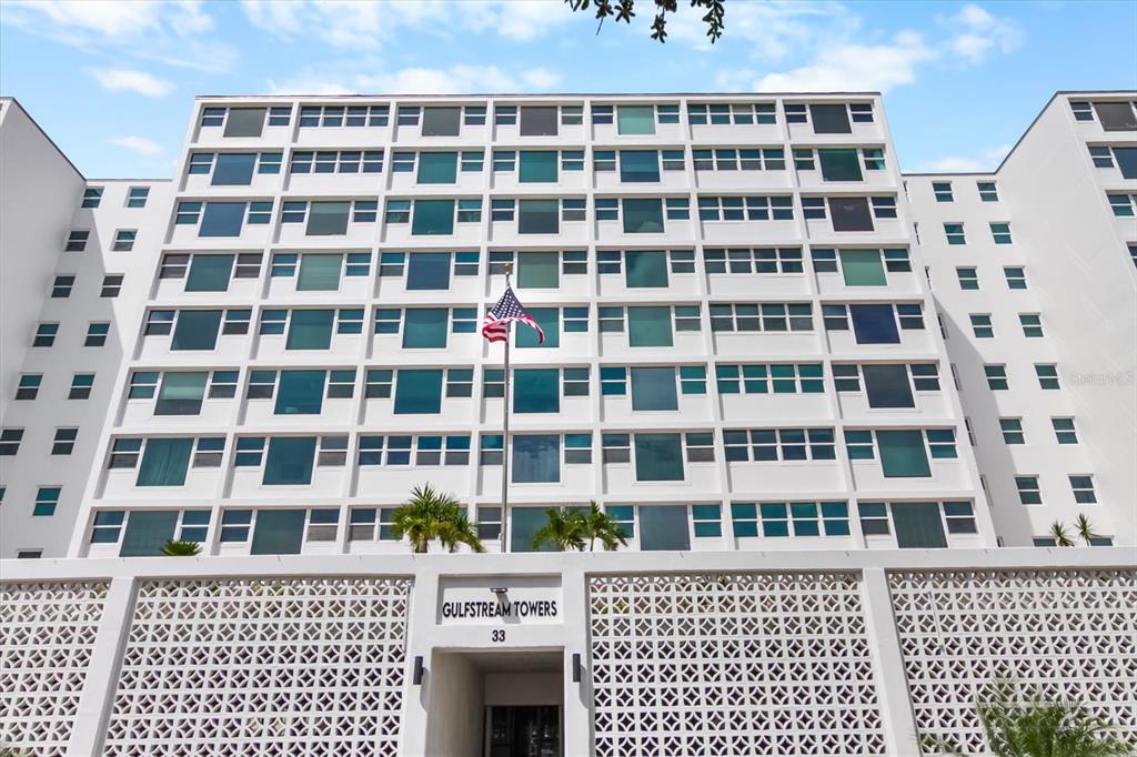 The exterior of a multi-story white apartment building with a decorative lattice screen at ground level — 33 S GULFSTREAM AVENUE UNIT 305, SARASOTA, FL