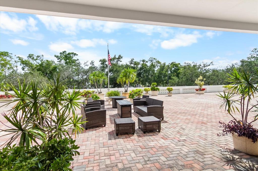 A spacious outdoor brick patio features wicker furniture, potted plants, and an American flag — 33 S GULFSTREAM AVENUE UNIT 305, SARASOTA, FL