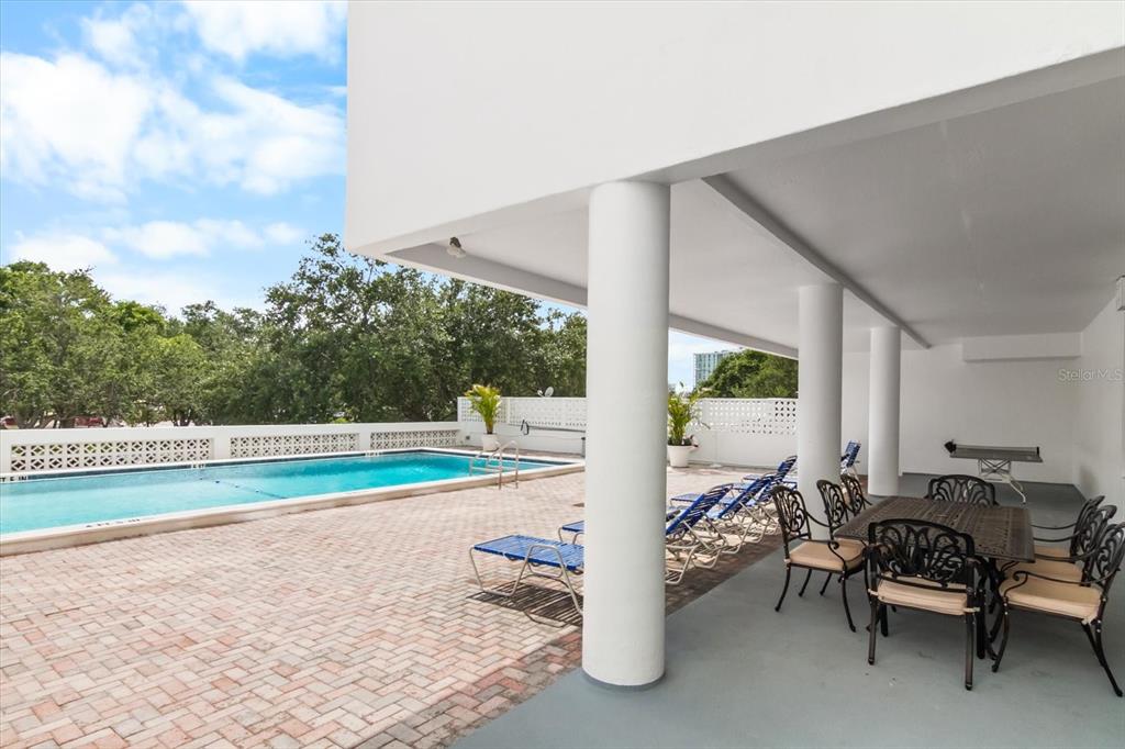 A covered patio with a dining set and lounge chairs overlooks an outdoor swimming pool — 33 S GULFSTREAM AVENUE UNIT 305, SARASOTA, FL