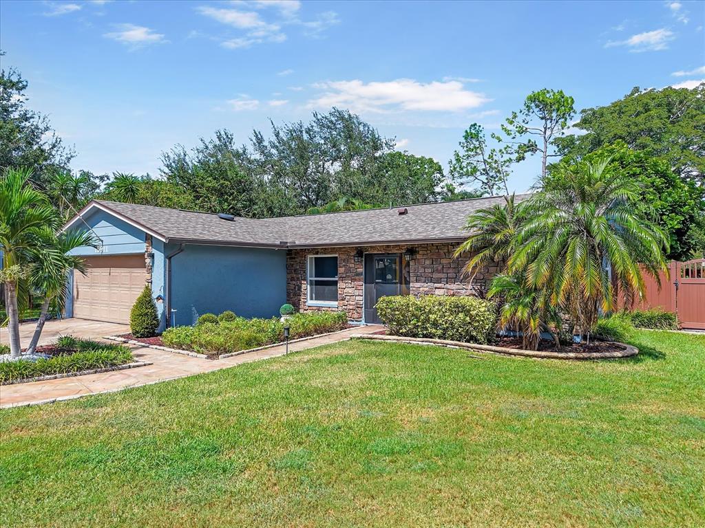 A single-story house with a stone facade, blue siding, a garage, and a front lawn — 15911 IRONWARE PLACE, TAMPA, FL