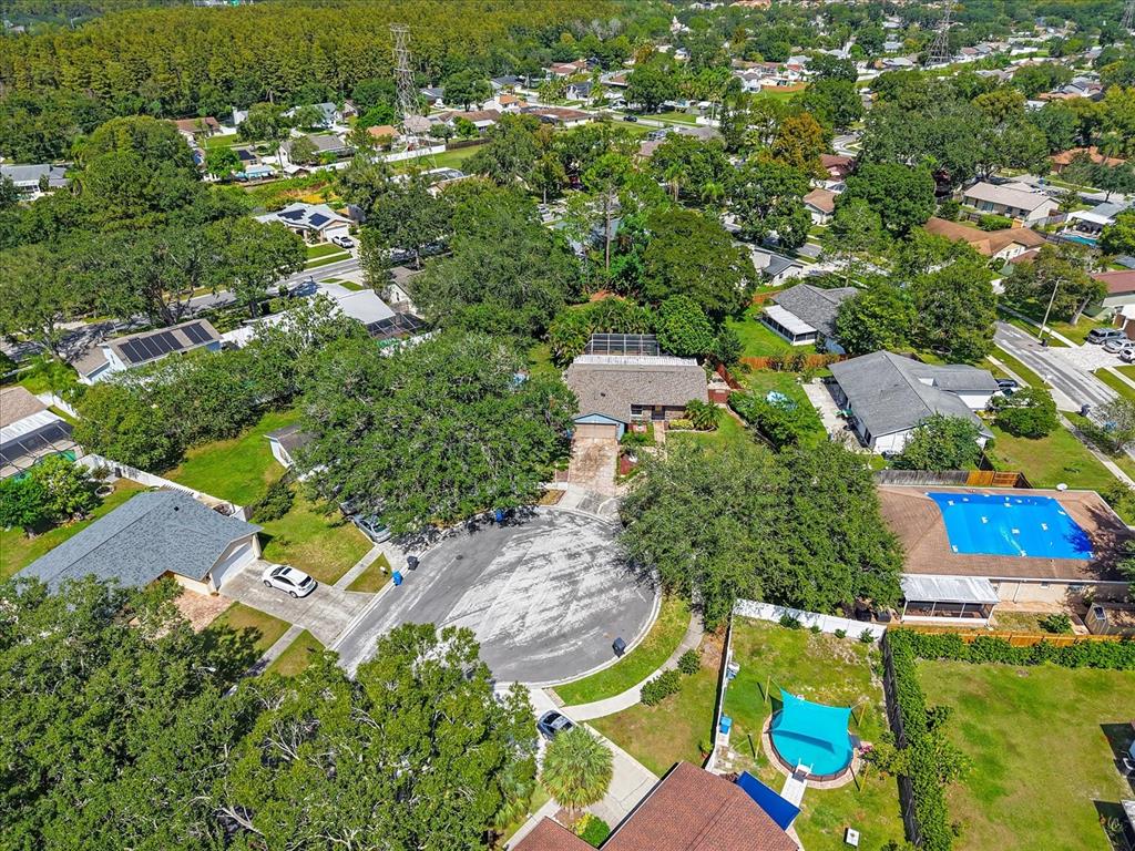 An aerial view shows a suburban neighborhood with houses, driveways, trees, and backyard swimming pools — 15911 IRONWARE PLACE, TAMPA, FL