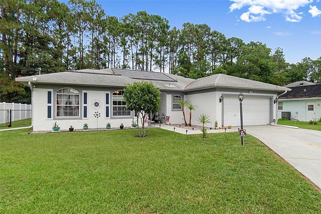 A single-story house with a white stucco exterior, a two-car garage, and a large lawn — 14 WILLS PLACE, PALM COAST, FL