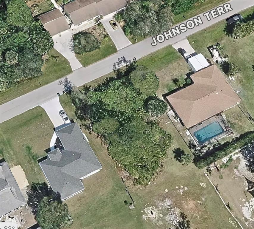 This aerial view shows a vacant residential lot situated between two houses on a street — 5290 JOHNSON TERRACE, PORT CHARLOTTE, FL