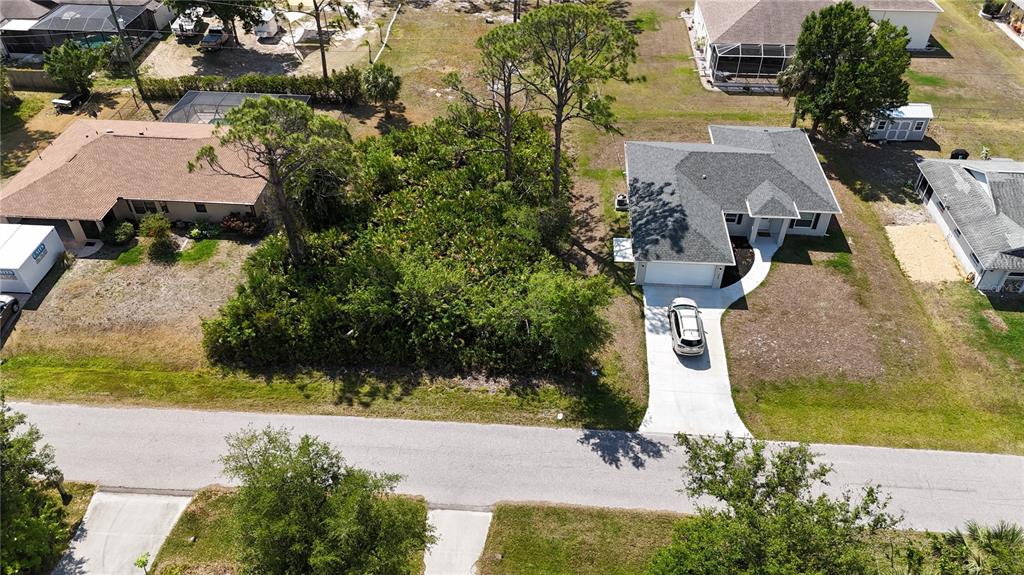 An aerial view shows a vacant, wooded lot situated between two single-family residential homes — 5290 JOHNSON TERRACE, PORT CHARLOTTE, FL
