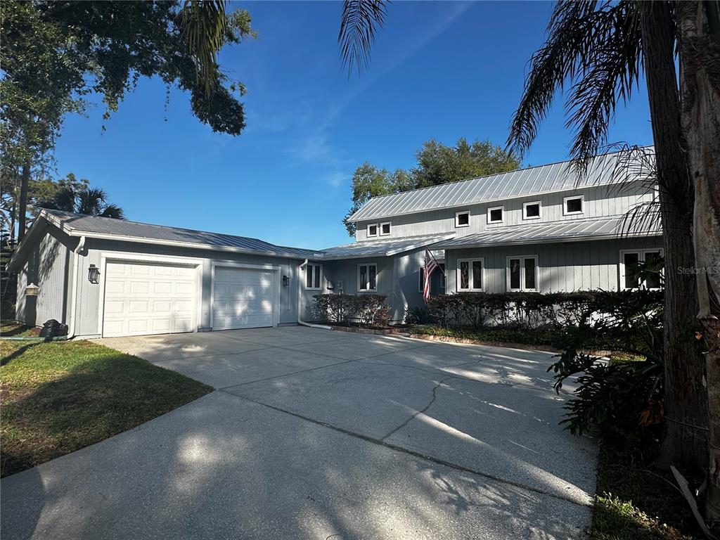 A two-story gray house with a metal roof and an attached two-car garage — 3421 BRIAN ROAD S, PALM HARBOR, FL