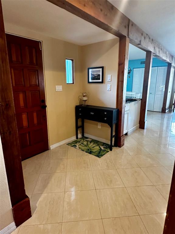An entryway features a wooden door, a black console table, and light-colored tile flooring — 3421 BRIAN ROAD S, PALM HARBOR, FL
