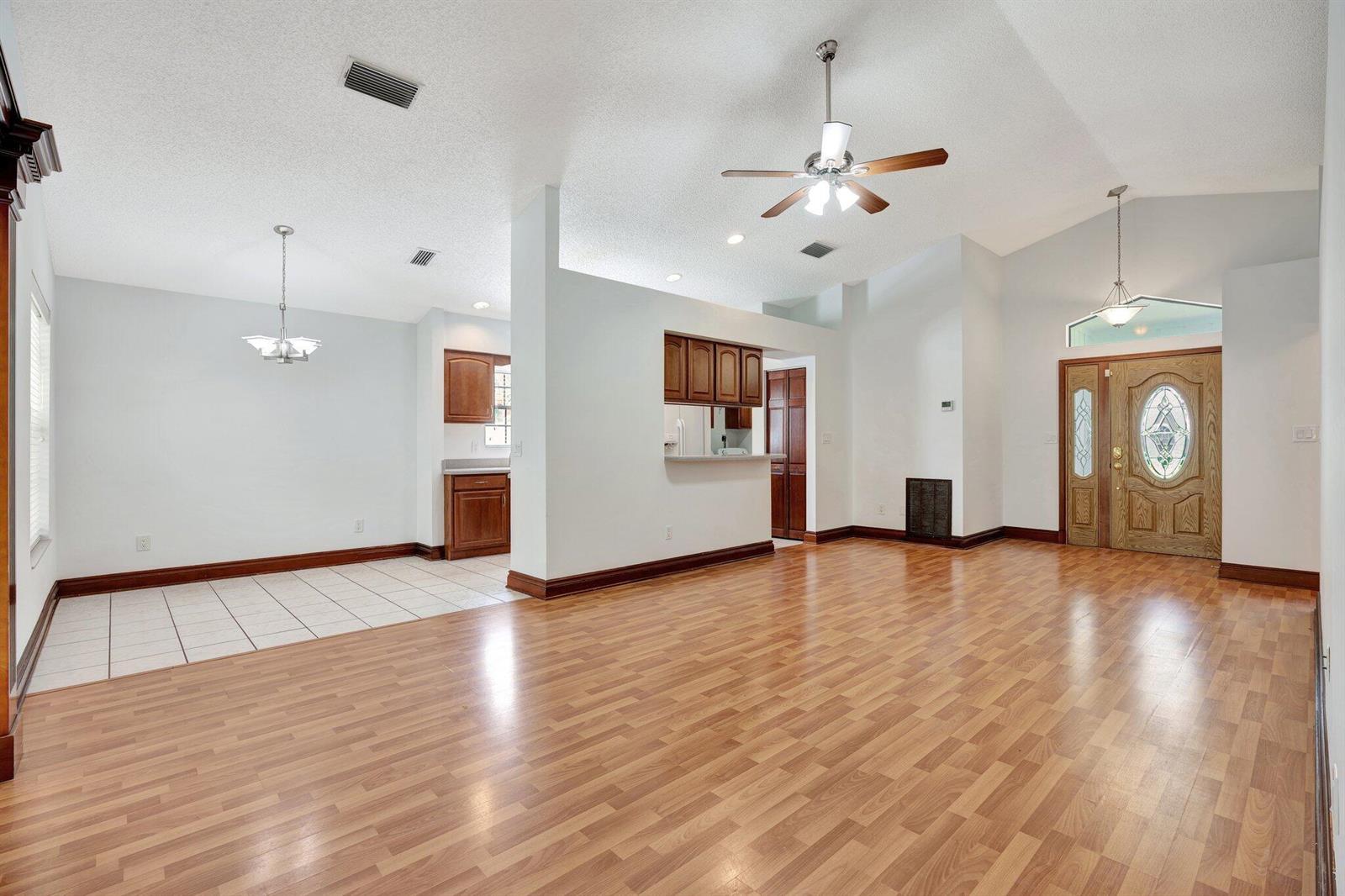 An open-concept living and dining area with wood-look flooring, a ceiling fan, and wood cabinets — 6149 Foster Street, Jupiter FL 33458, JUPITER, FL